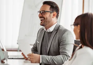 Man Smiling while holding a piece of paper in a meeting